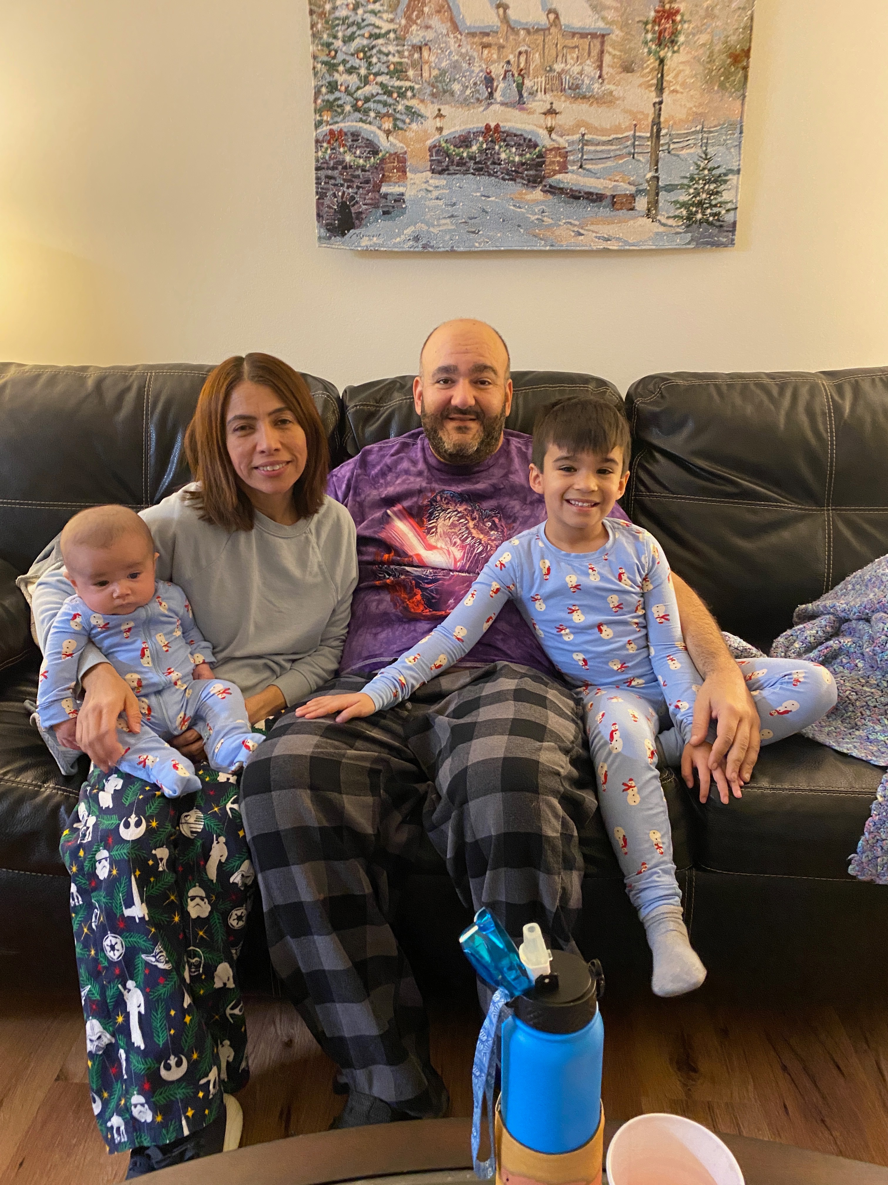 A picture of Fred with his family, smiling at home on their couch.